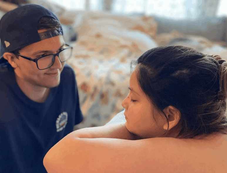 Partner providing emotional support to a laboring mother during home birth, demonstrating compassionate care and guidance from a midwife dallas.